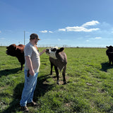Man interacting with a cow in a grassy field on a clear day