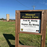 Wooden sign for Missouri Century Farm with a silo in the background